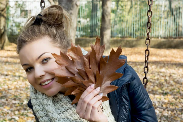 Belle adolescente souriante avec des feuilles de chêne brun — Photo