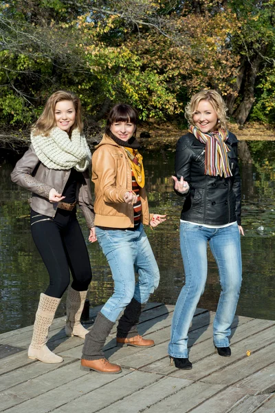 Tre bella donna gioiosa in posa su un molo al lago — Foto Stock