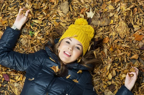 Молодая улыбающаяся девочка-подросток лежит в осенних листьях — стоковое фото