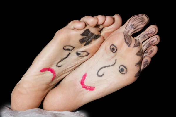 Painted faces on the woman's feet