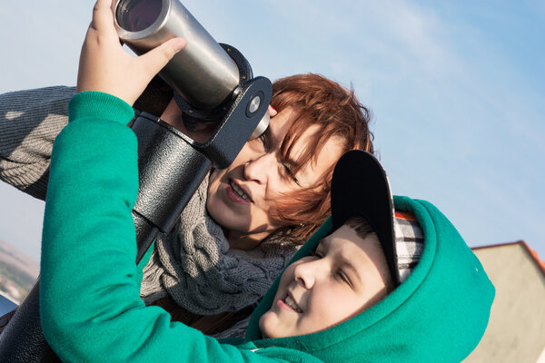 Young boy with her grandmother looking through a telescope