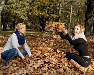 Sarı yaprakları atan iki genç beyaz kadın