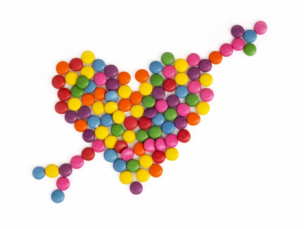 Heart with arrow made of colored smarties — Stock Photo, Image