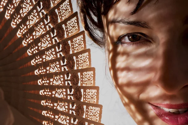 Mulher bonita na sombra com um fã tradicional — Fotografia de Stock