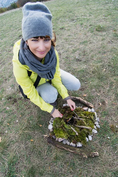 Young woman and extinct campfire lined with green moss — Stock Photo, Image