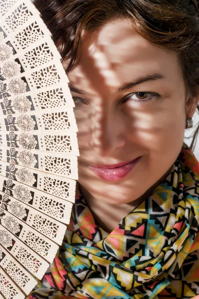 Lachende vrouw peeks uit achter traditionele ventilator — Stockfoto