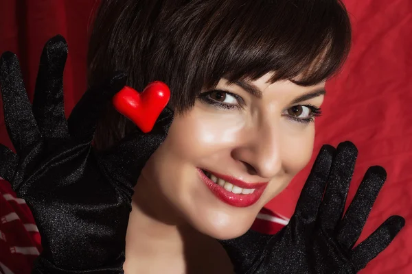 Krásná mladá usměvavá žena s červeným srdcem v ruce — Stock fotografie