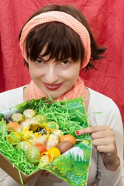 Mujer sonriente sosteniendo una cesta con huevos pintados de Pascua —  Fotos de Stock