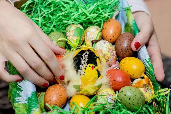 Woman holding a basket with easter painted eggs in the hands — Stock Photo, Image