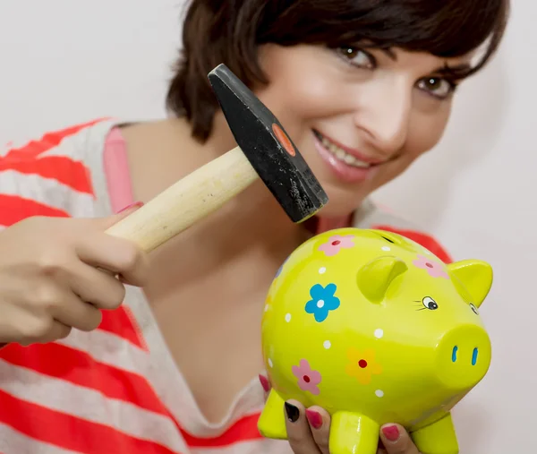 Young woman breaks a porcelain piggy bank with a hammer — Stock Photo, Image