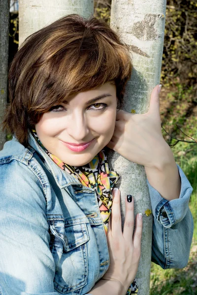 Beautiful woman posing with tree trunk — Stock Photo, Image