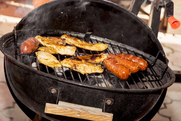 Salsicce e carne di pollo su una griglia — Foto Stock