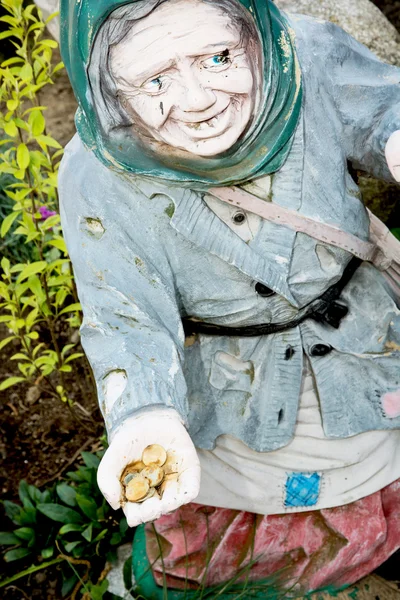Statua giardino di una vecchia donna con monete in mano — Foto Stock