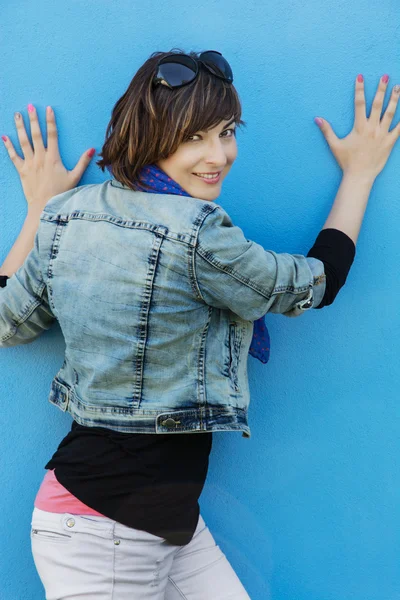 Krásná bruneta pózuje před modrou zeď — Stock fotografie