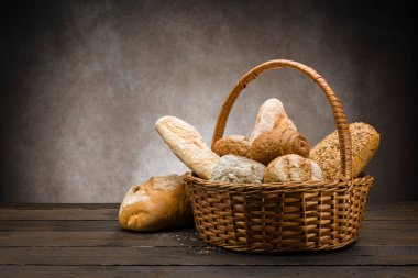 Hasır sepetin içinde ahşap masada pişmiş ekmek çeşitleri.
