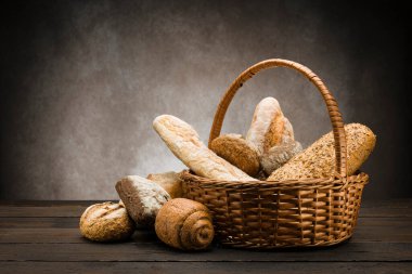 Hasır sepetin içinde ahşap masada pişmiş ekmek çeşitleri.