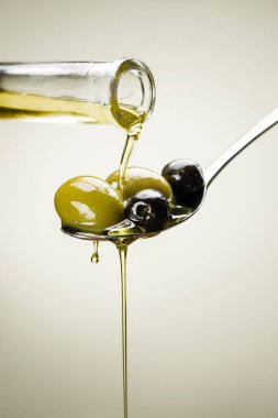 Büyük yeşil ve siyah zeytinler kaşık yağı damlatıyor