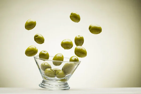 Big Green Olives Jumping Out Glass Bowl Colored Background — Stockfoto