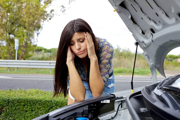 Mujer desesperada mirando el motor roto de su coche — Foto de Stock