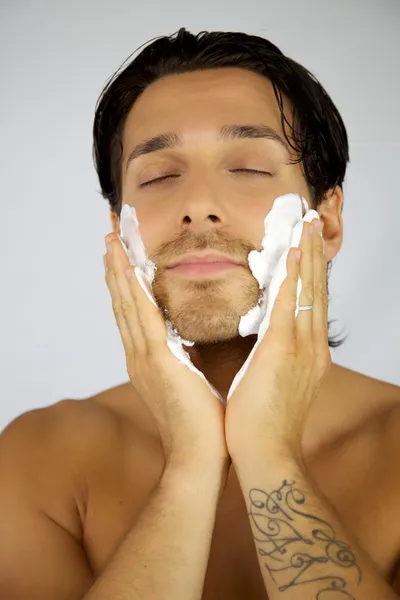 Feliz hombre poniendo crema de afeitar en su cara — Foto de Stock