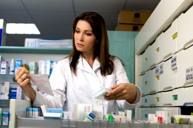 Beautiful female pharmacist searching for medicine