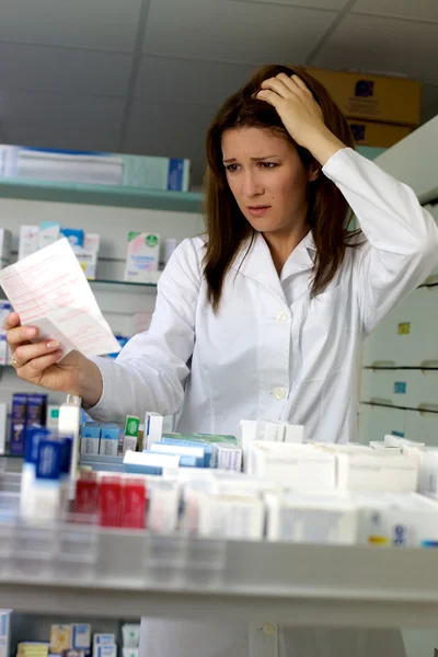 Bezorgd vrouwelijke apotheker kijken naar voorschrift niet wetend wat te doen — Stockfoto