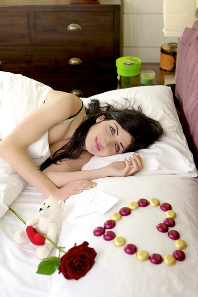 Happy beautiful woman in bed with romantic gifts from boyfriend — Stock Photo, Image