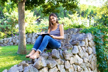 Park kitap ile gülümseyen çekici üniversite öğrencisi