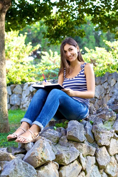 Estudante universitário feliz ler livro em um parque — Fotografia de Stock