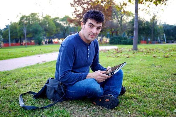 Smiling good looking man with tablet in park — Stock Photo, Image