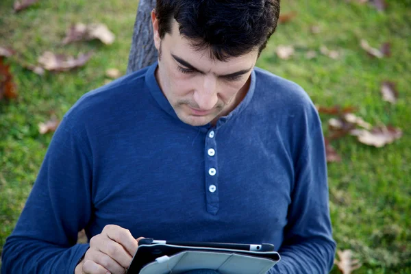 Handsome man working with tablet in park in autumn — Stock Photo, Image