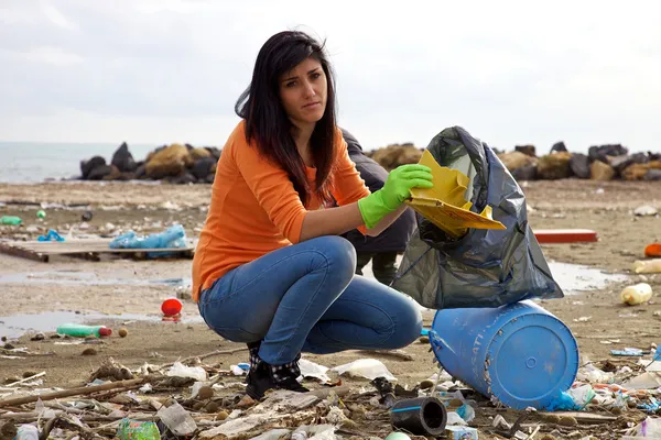 Jonge vrouw probeert te schoon vuil strand ecologische ramp — Stockfoto