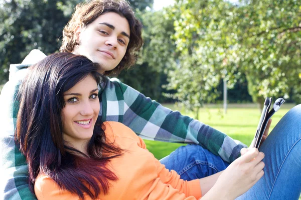 Casal sorridente com tablet pad no parque — Fotografia de Stock