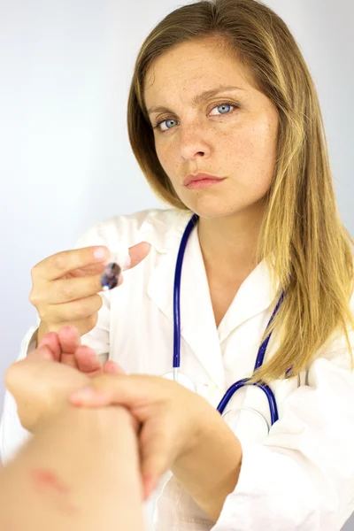 Médica do sexo feminino que segura o braço com sangue e seringa — Fotografia de Stock