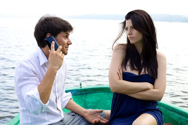 Несчастная женщина смотрит парень улыбается по телефону — стоковое фото