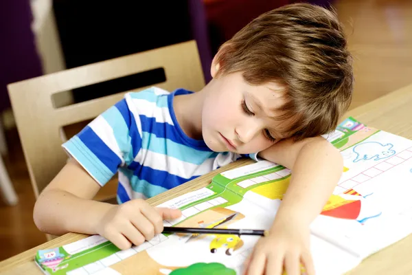 Jonge jongen in slaap vallen tijdens huiswerk thuis — Stockfoto