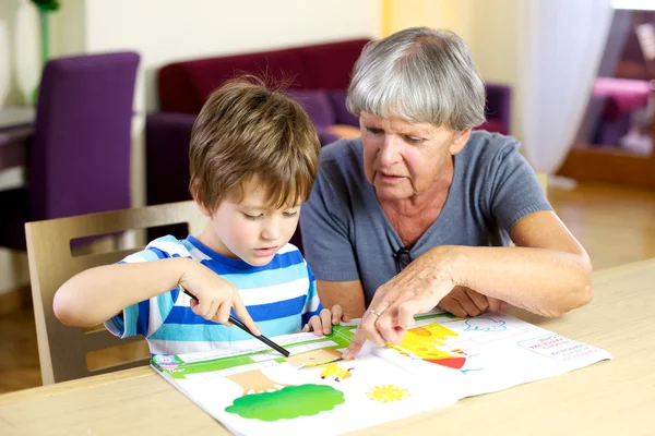 Happy grandmother doing homework with grandson — Stock Photo, Image