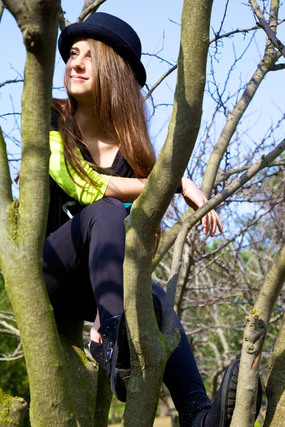 Young teenager sitting on tree thinking smiling — Stock Photo, Image