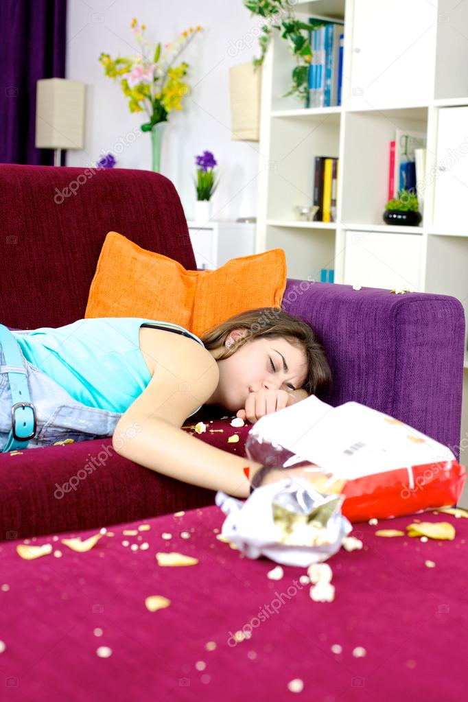 Girl teenager sleeping on couch at home surrounded by chips
