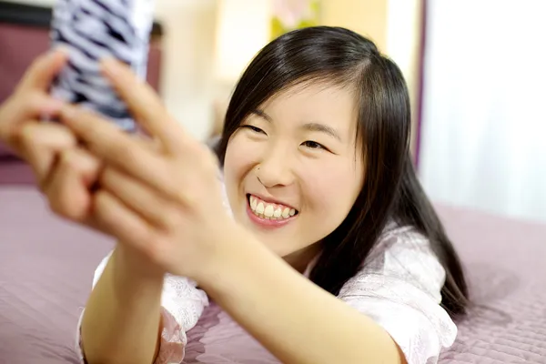 Bonito ásia americano mulher no cama tomando selfie sorrindo — Fotografia de Stock