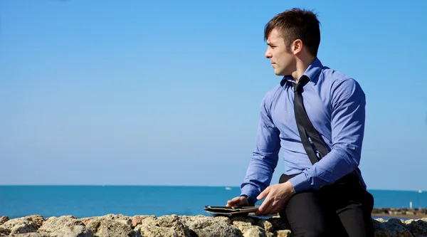 Bonito empresário relaxante com tablet em frente ao oceano — Fotografia de Stock