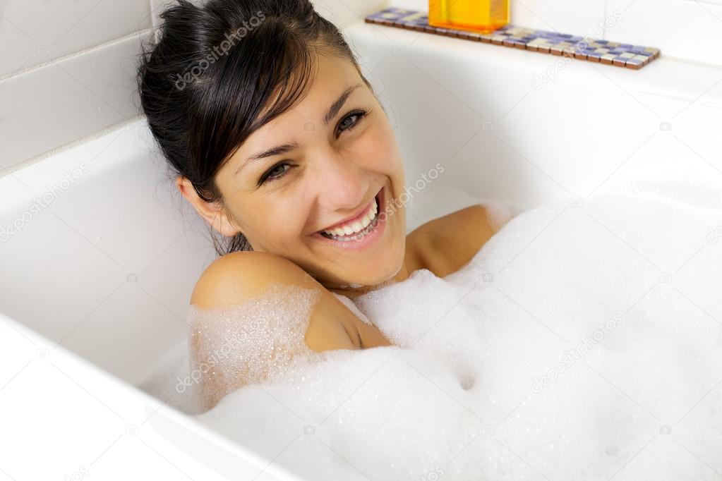 Smiling beautiful young woman in bathtub full of foam