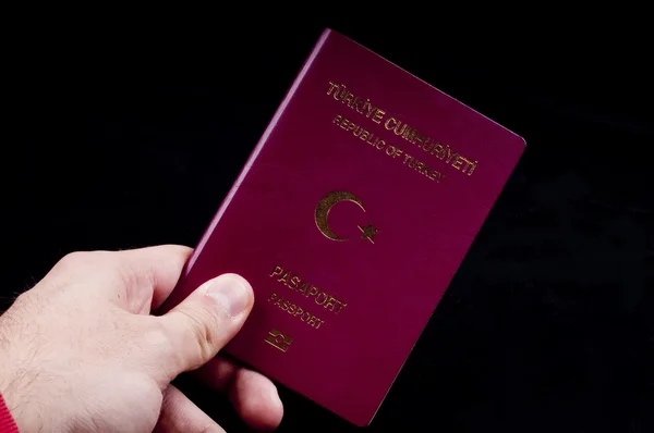 Τύπος που ασκεί την τουριστική τουρκικό διαβατήριο στο μαύρο υπόβαθρο Φωτογραφία Αρχείου