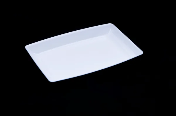 Siyah zemin üzerine beyaz dikdörtgen plastik tabak — Stok fotoğraf