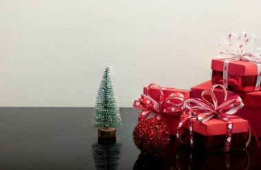 Yansıtıcı bir arka planda hediye kutuları ve Noel süslemeleri.