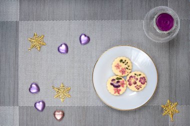 Bir tabak yenilebilir çiçek bisküvisi ve kokulu mumla Noel masası süslemeleri..