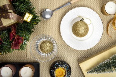 Altın rengi takılar ile bir Noel masası ayarlarının üst görünümü.