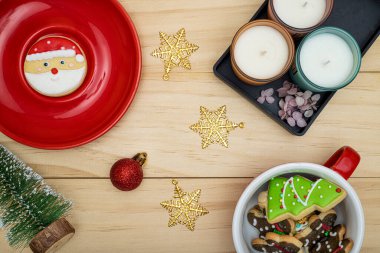 Şeker kaplı bisküviler ve Noel temalı kurabiyeler kokulu mumlar ve ahşap bir arka planda Noel süsleri..