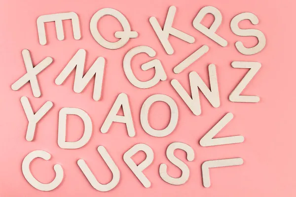 ピンクの紙の背景に木製のアルファベット文字 木製の白い文字の多く — ストック写真
