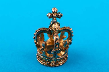 Mavi kağıttan arka planda küçük altın taç. Makro.